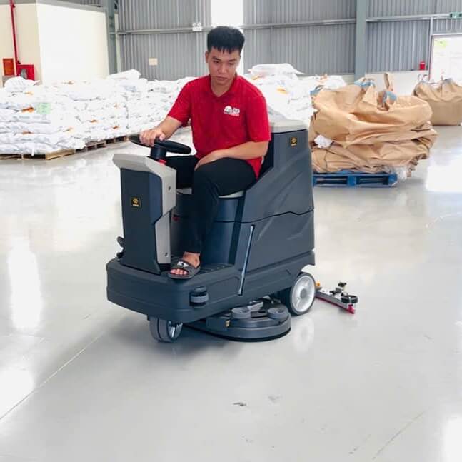 Máy chà sàn ngồi lái Krapo M2913 Chi tiết Krapo M2913, hệ thống điều khiển và bàn chải đang làm sạch sàn nhà kho.